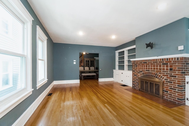 312 Columbia Ave, Palmerton, PA 18071 - unfurnished living room with wood finished floors, healthy amount of natural light, built in features, and a brick fireplace