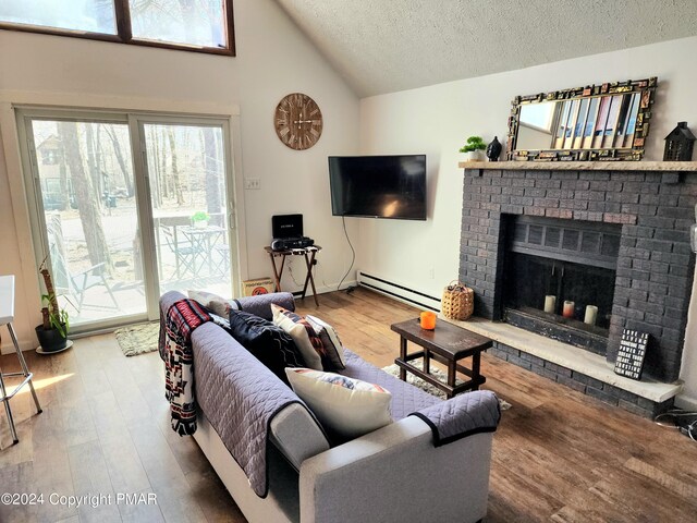 living room featuring baseboard heating, lofted ceiling, a textured ceiling, and hardwood / wood-style flooring