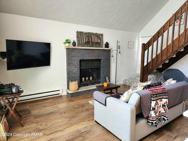 living room featuring baseboard heating, hardwood / wood-style floors, a brick fireplace, and a textured ceiling