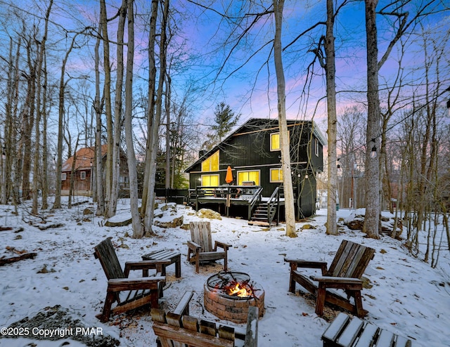 snowy yard with an outdoor fire pit, stairway, and a wooden deck