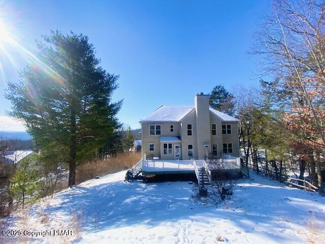 snow covered rear of property featuring a deck