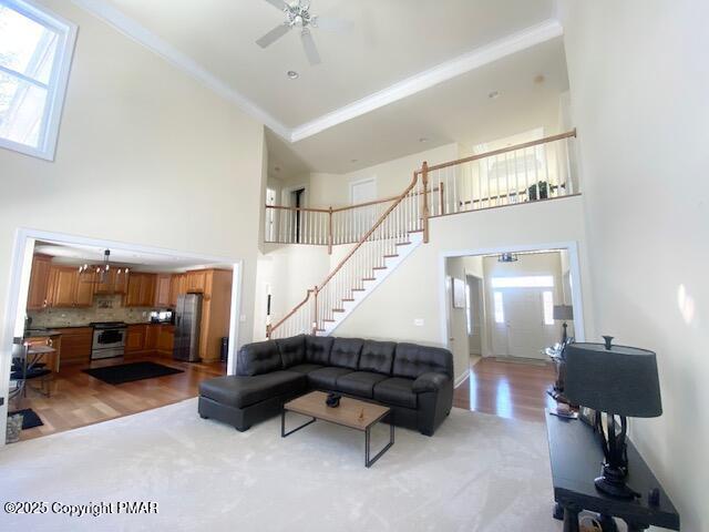 living room featuring plenty of natural light, a high ceiling, ceiling fan, and ornamental molding