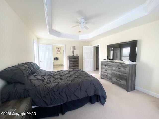 carpeted bedroom with ceiling fan and a raised ceiling