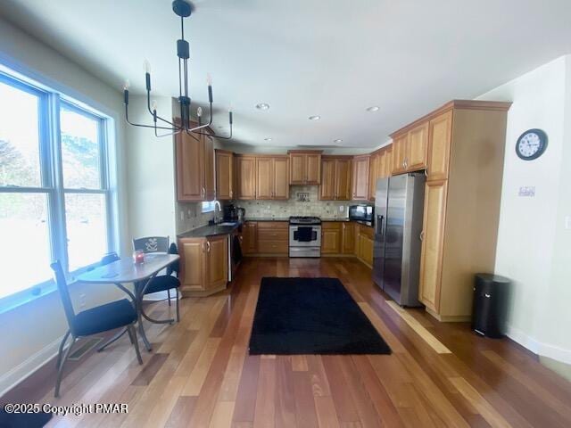 kitchen featuring a notable chandelier, tasteful backsplash, hardwood / wood-style flooring, sink, and stainless steel appliances