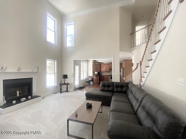 carpeted living room with a towering ceiling and ornamental molding