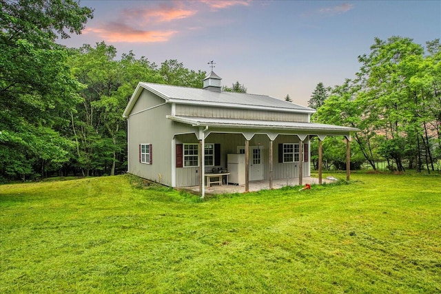 188 Cress Dr, Saylorsburg, PA 18353 - back of house at dusk featuring a yard, a metal roof, a patio area, and a chimney