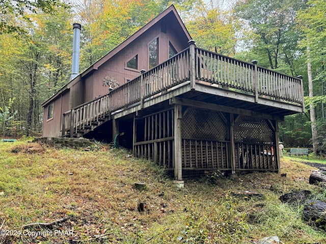 view of side of property featuring a deck, stairway, and a view of trees