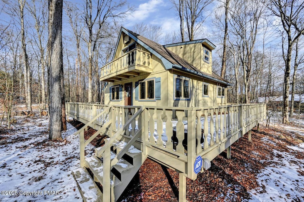 view of snowy exterior with a wooden deck and a balcony