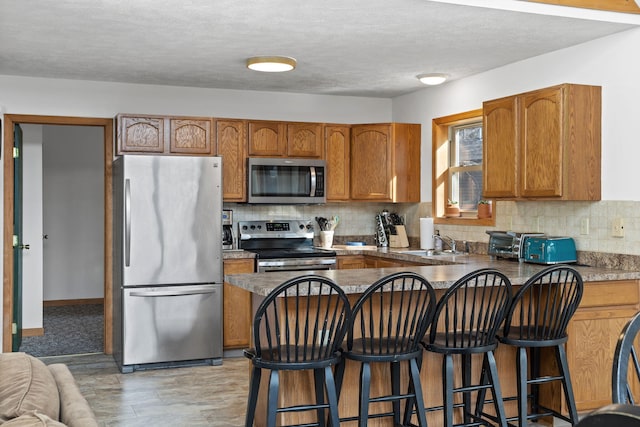 225 N Arrow Dr, Pocono Lake, PA 18347 - kitchen featuring stainless steel appliances, brown cabinets, a peninsula, backsplash, and a breakfast bar