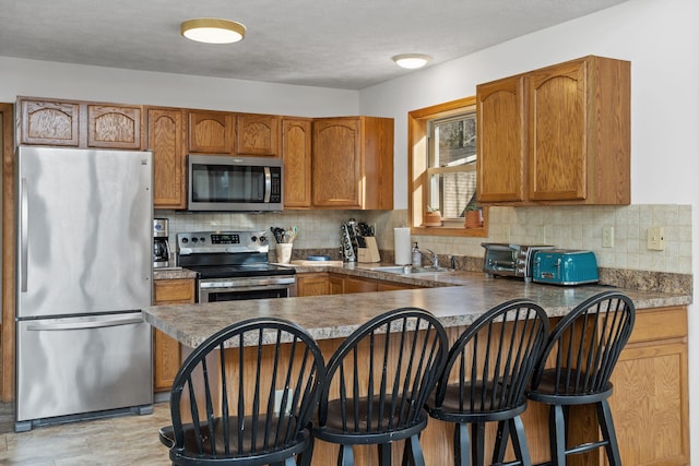 225 N Arrow Dr, Pocono Lake, PA 18347 - kitchen with appliances with stainless steel finishes, brown cabinets, decorative backsplash, and a peninsula