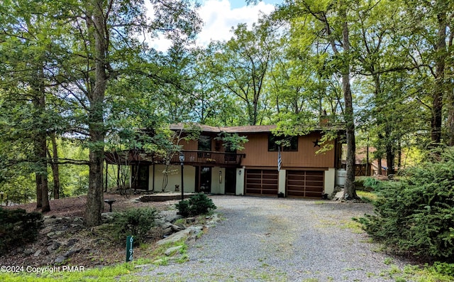 rustic home featuring driveway, a wooden deck, and a garage