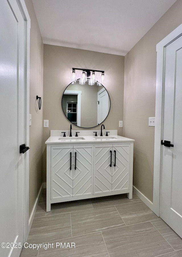 bathroom featuring double vanity, a sink, and baseboards