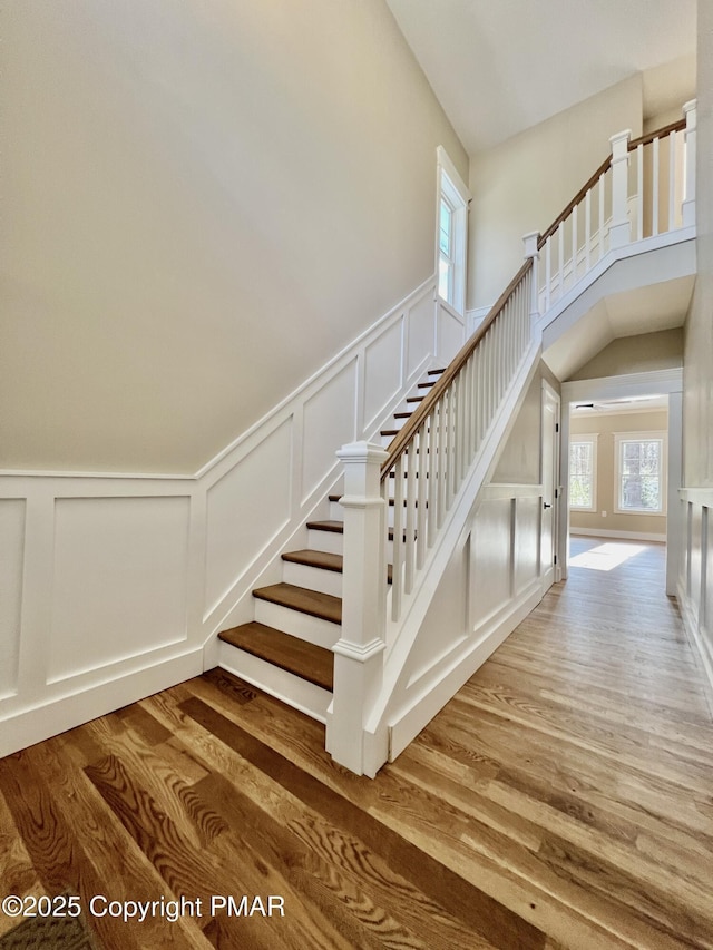 stairs featuring a decorative wall, a high ceiling, and wood finished floors