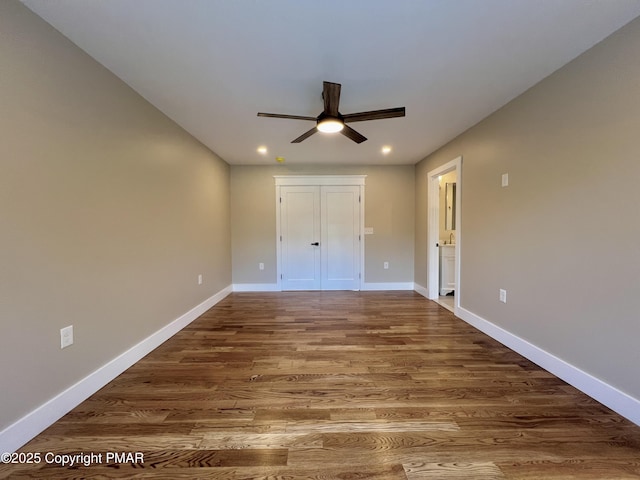 unfurnished bedroom featuring dark wood-style flooring, recessed lighting, ceiling fan, ensuite bath, and baseboards