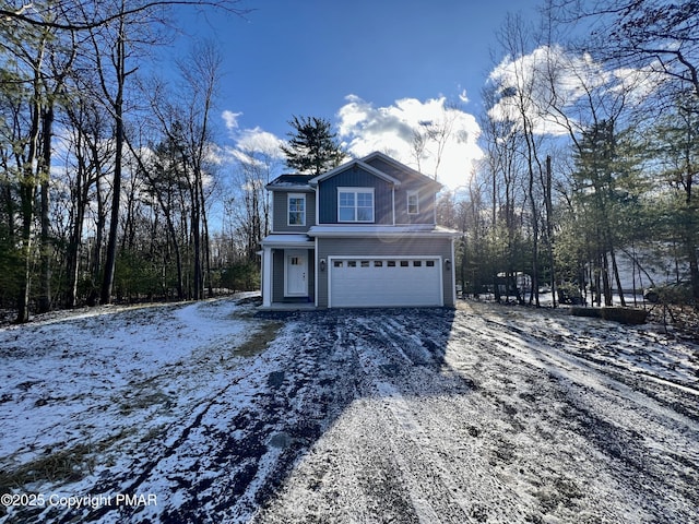 view of snow covered exterior with board and batten siding, gravel driveway, and an attached garage