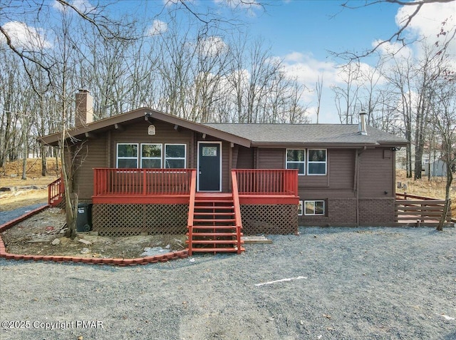 view of front of property with a deck, a chimney, and stairs