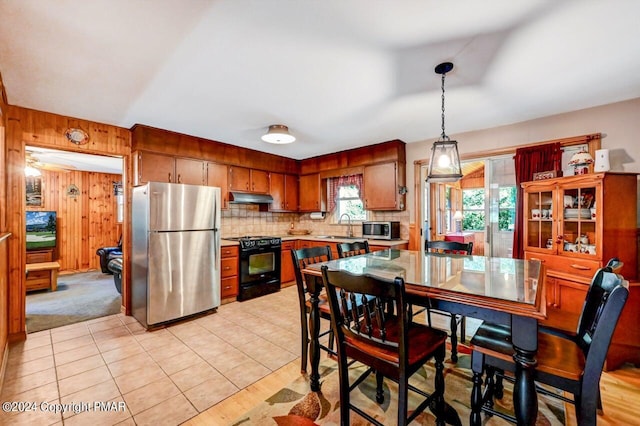 kitchen featuring a sink, stainless steel appliances, light countertops, under cabinet range hood, and backsplash