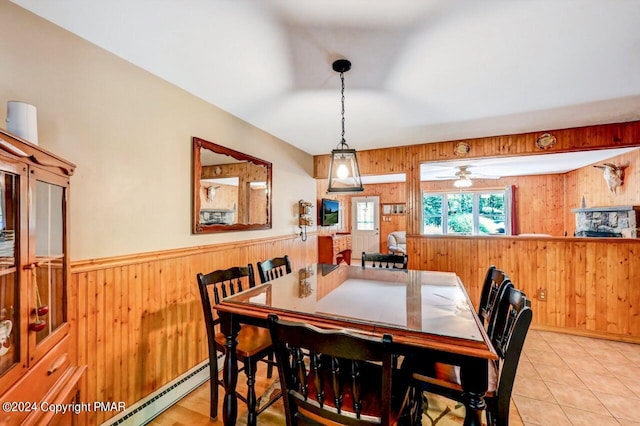 dining room with a wainscoted wall, wooden walls, baseboard heating, and tile patterned floors