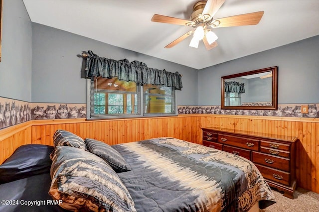 bedroom with a wainscoted wall, ceiling fan, wood walls, and carpet