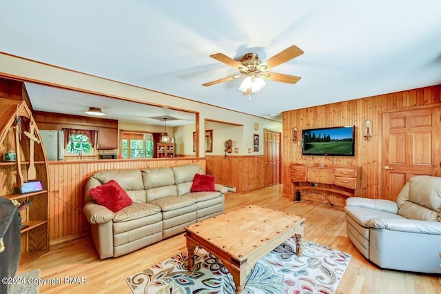 living room featuring ceiling fan, wood walls, and wood finished floors