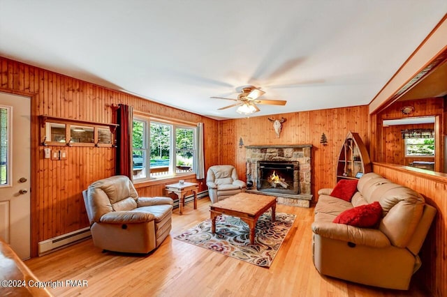 living area with a baseboard heating unit, wood walls, a fireplace, and wood finished floors