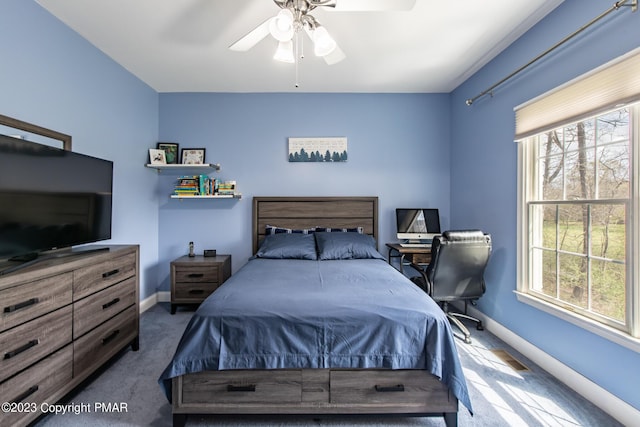 carpeted bedroom with multiple windows, a ceiling fan, and baseboards