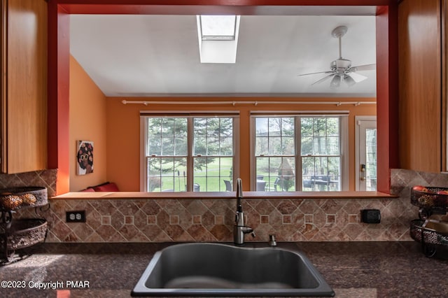 kitchen featuring dark countertops, plenty of natural light, tasteful backsplash, and a sink