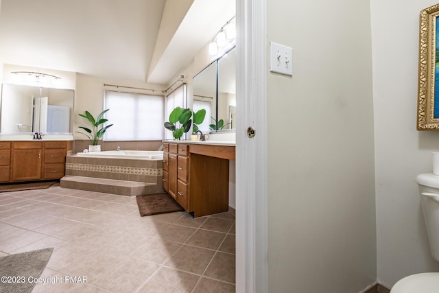 bathroom featuring a sink, two vanities, a bath, and tile patterned floors