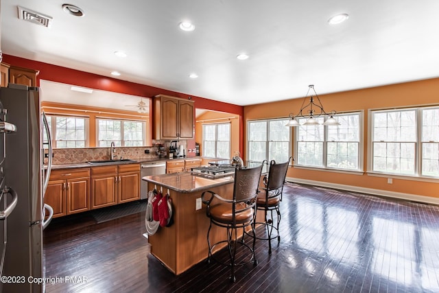 kitchen with visible vents, appliances with stainless steel finishes, a breakfast bar, dark wood-type flooring, and a sink