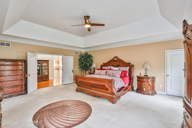 bedroom featuring a raised ceiling, visible vents, and light colored carpet