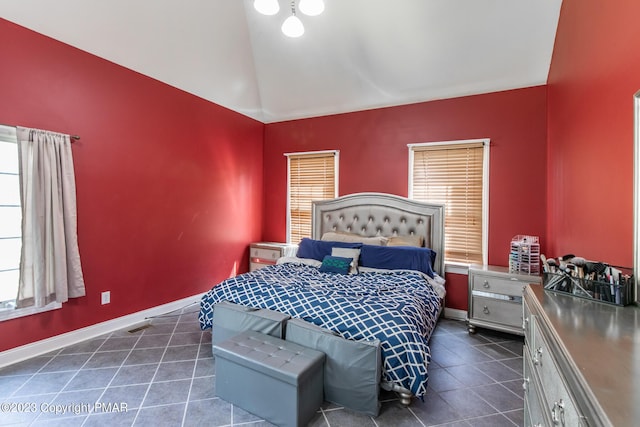 bedroom with vaulted ceiling, dark tile patterned floors, visible vents, and baseboards