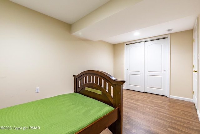 bedroom with a closet, baseboards, and wood finished floors