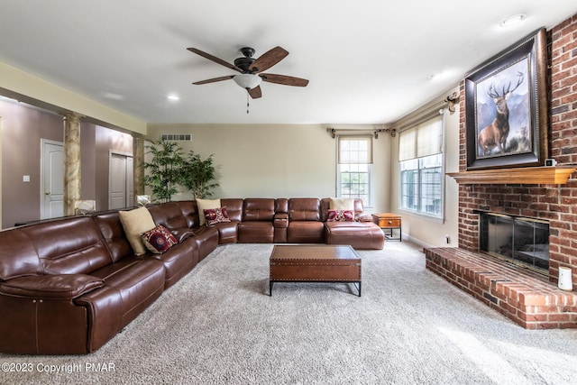 carpeted living area featuring a fireplace, decorative columns, visible vents, ceiling fan, and baseboards