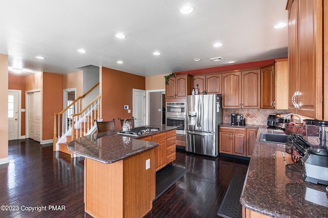 kitchen with a kitchen island, appliances with stainless steel finishes, dark wood-type flooring, and a sink