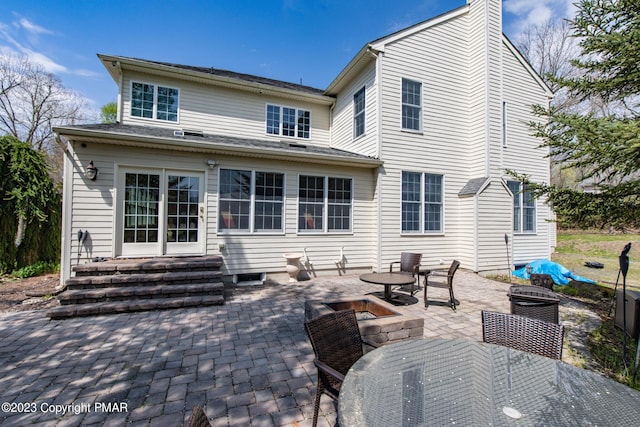 rear view of house with entry steps, a patio, outdoor dining area, and a chimney