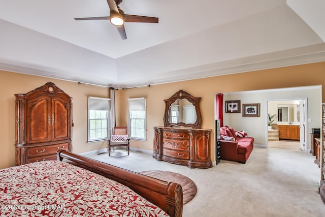 bedroom with light carpet, a raised ceiling, connected bathroom, and baseboards