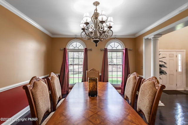 dining room with wood finished floors, baseboards, an inviting chandelier, decorative columns, and crown molding