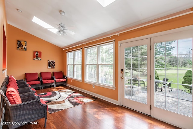 living area with ceiling fan, lofted ceiling with skylight, wood finished floors, and baseboards