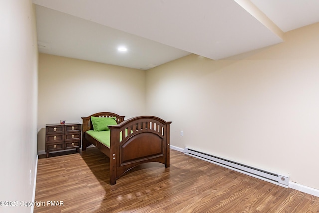 bedroom featuring a baseboard radiator, baseboards, and wood finished floors