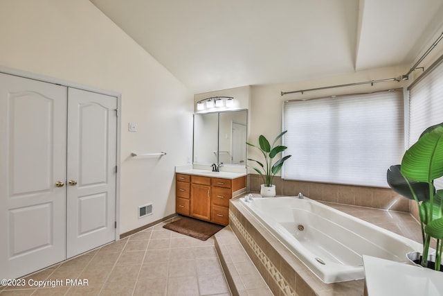 bathroom with visible vents, vaulted ceiling, vanity, a tub with jets, and tile patterned floors