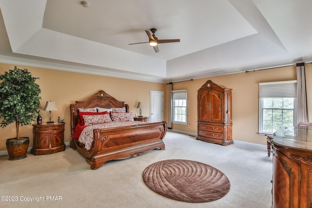 carpeted bedroom featuring ceiling fan, baseboards, and a raised ceiling