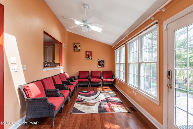 living room featuring plenty of natural light, vaulted ceiling, baseboards, and wood finished floors