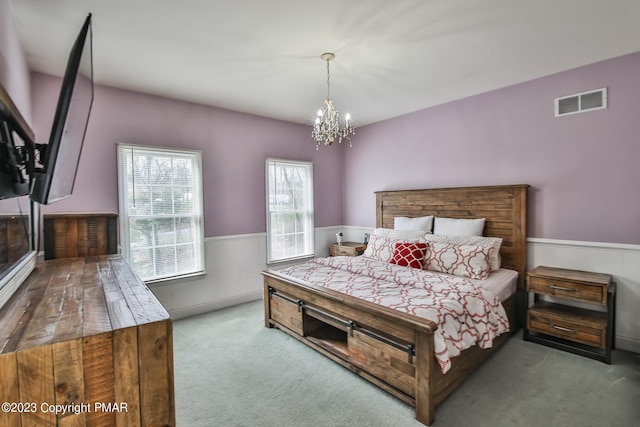 carpeted bedroom featuring wainscoting, visible vents, and a notable chandelier