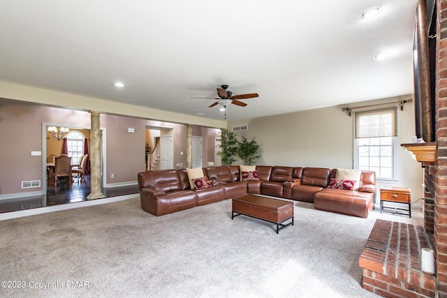 carpeted living area with a brick fireplace, recessed lighting, visible vents, and ceiling fan with notable chandelier