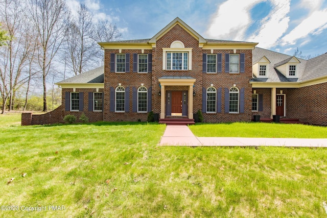 colonial home with a front yard and brick siding