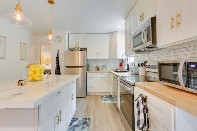 1490 Waterfront Dr, Tobyhanna, PA 18466 - kitchen featuring appliances with stainless steel finishes, a sink, light wood-style flooring, white cabinets, and decorative backsplash