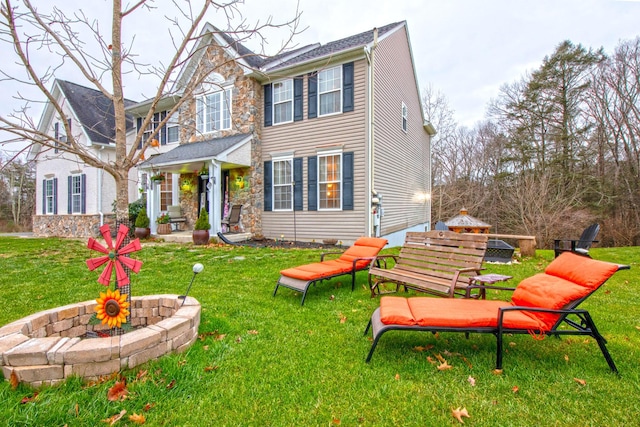 back of property with a yard and stone siding