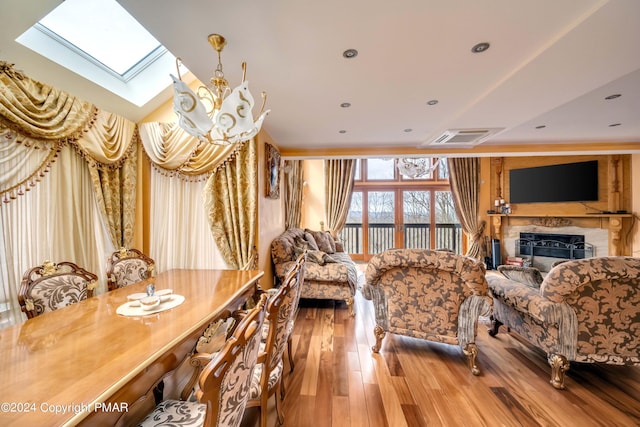 interior space with a skylight, a fireplace, recessed lighting, visible vents, and wood finished floors