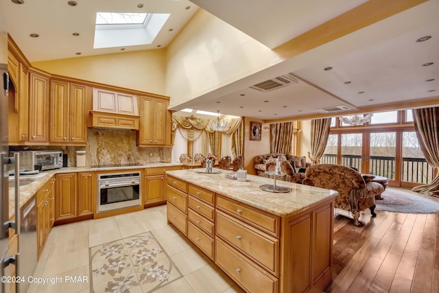 kitchen with visible vents, backsplash, appliances with stainless steel finishes, an island with sink, and light stone countertops