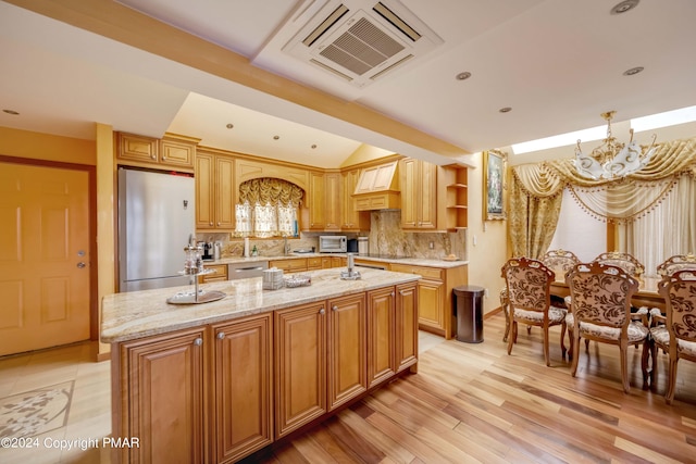 kitchen featuring tasteful backsplash, a center island, fridge, open shelves, and a notable chandelier